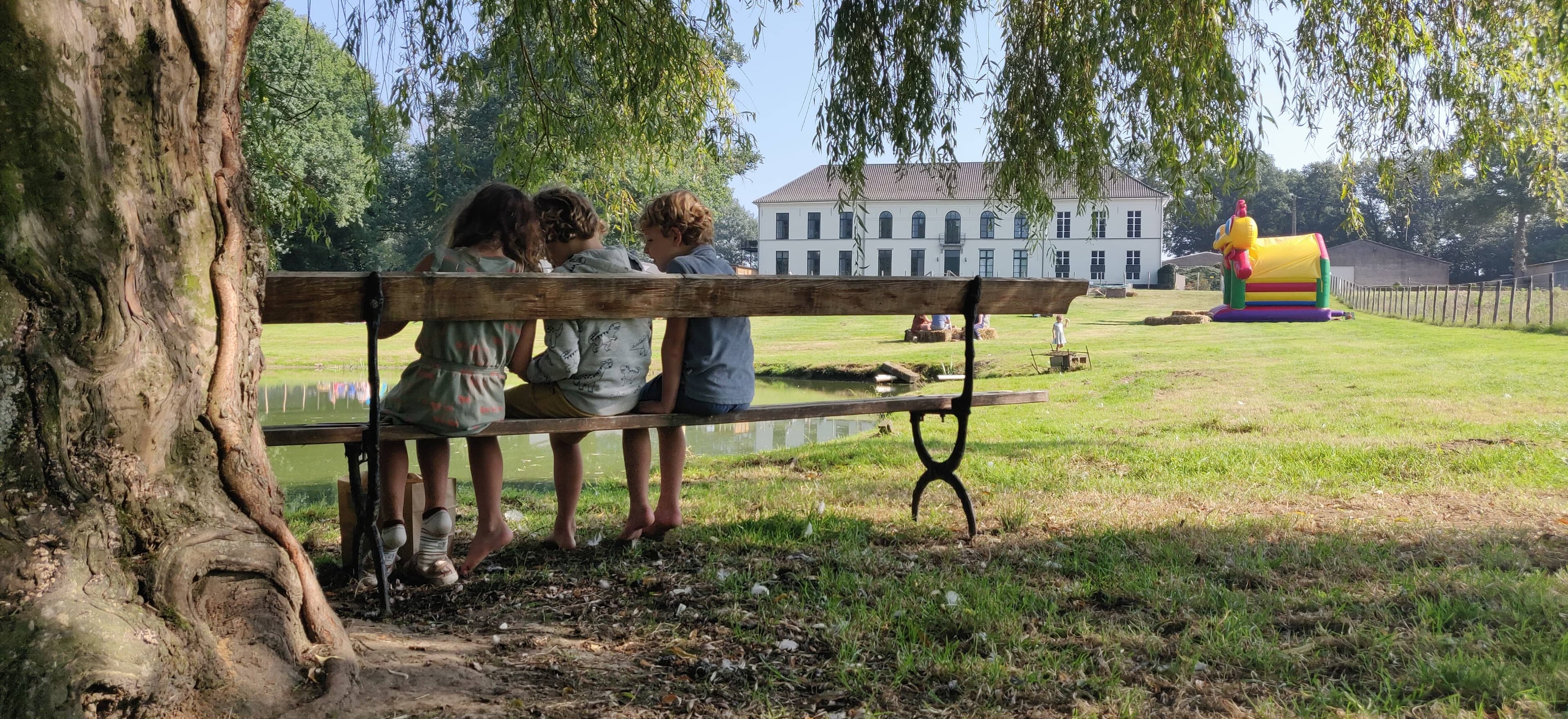 Hoofdgebouw en erf van de Lianko-hoeve omringd door bomen en groen